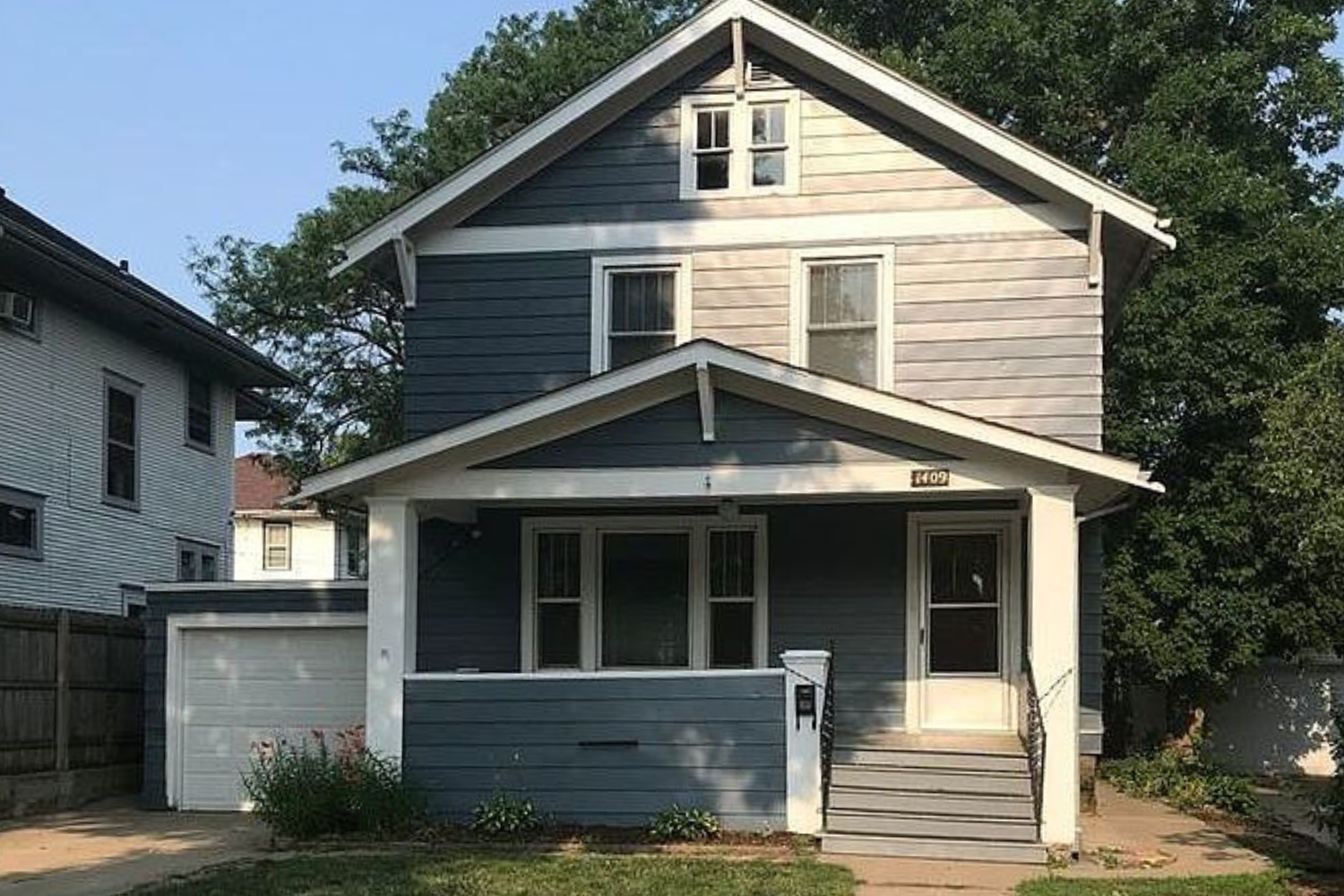 A two-story residential home with blue siding and white trim, featuring a front porch and an attached single-car garage, located at 1409 S Norton Ave, Sioux Falls, SD.