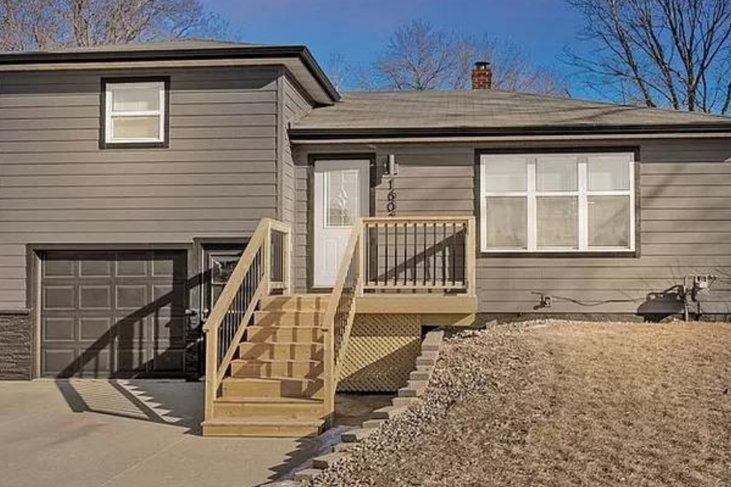 A contemporary single-level home with dark gray siding and a newly constructed wooden front deck, featuring an attached garage, located at 1608 S Willow Ave, Sioux Falls, SD.