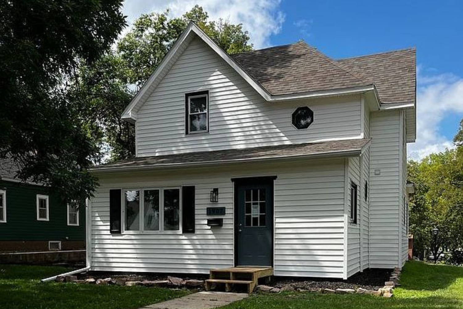 A newly renovated traditional home with white siding and contrasting dark shutters, featuring a gable roof and small wooden entry steps, located at 1907 S Prairie Ave, Sioux Falls, SD.