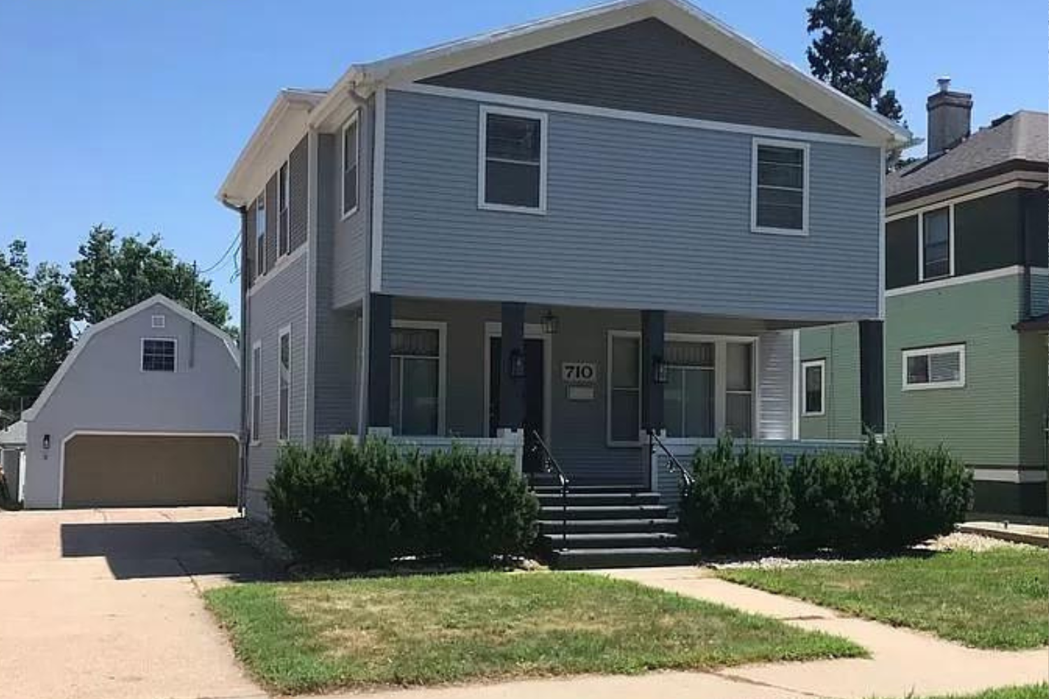 A modern two-story home with gray siding, white trim, and a covered front entrance, alongside a detached two-car garage, located at 710 S Dakota Ave, Sioux Falls, SD.