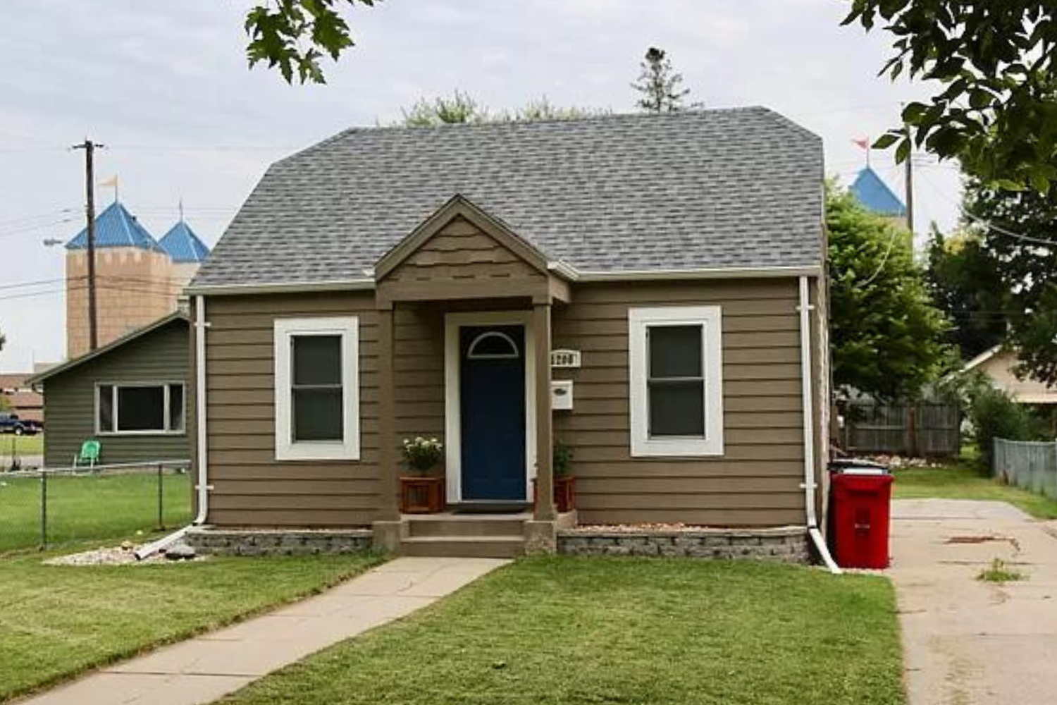 A newly renovated traditional home with white siding and contrasting dark shutters, featuring a gable roof and small wooden entry steps, located at 1907 S Prairie Ave, Sioux Falls, SD.