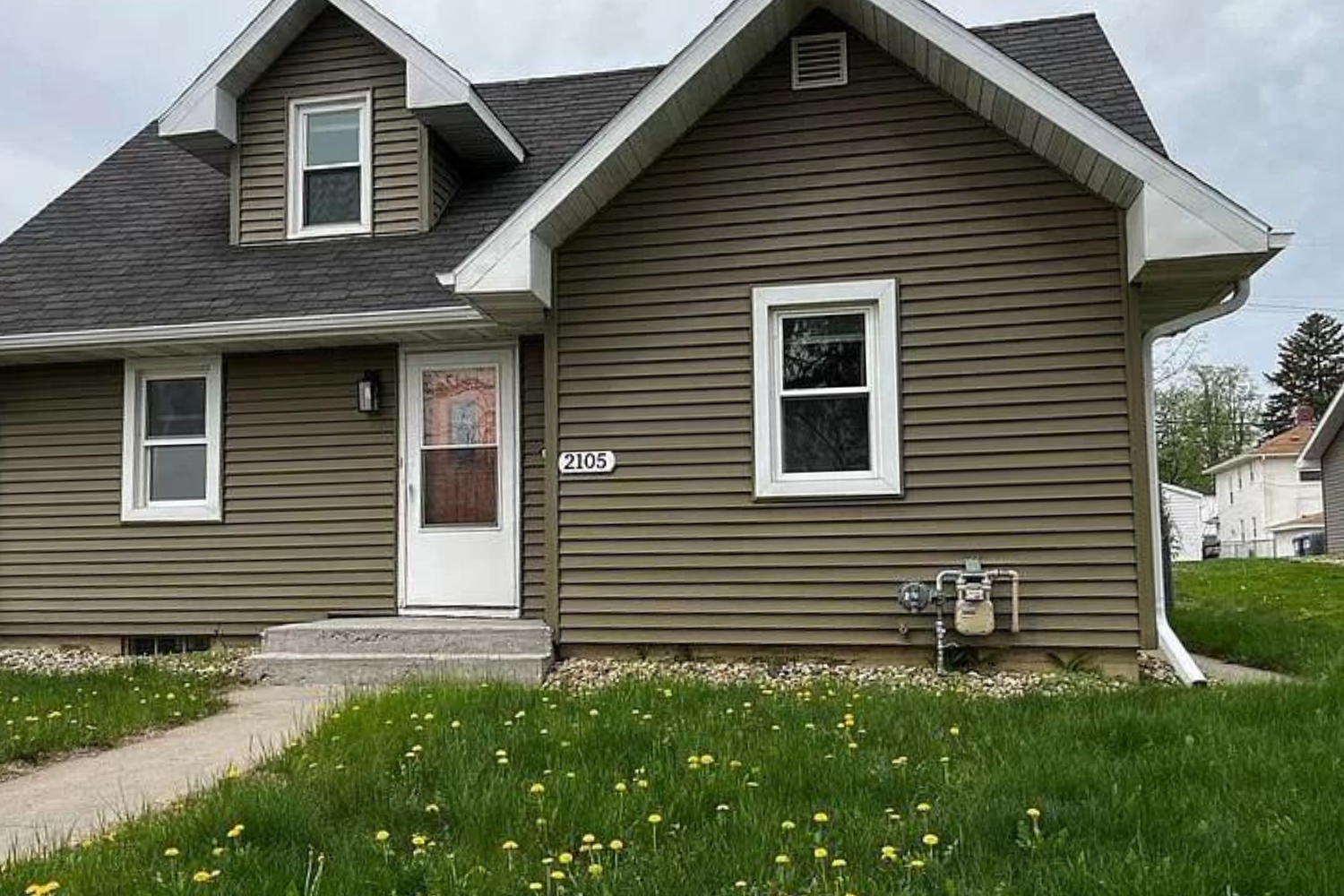 A newly renovated traditional home with white siding and contrasting dark shutters, featuring a gable roof and small wooden entry steps, located at 1907 S Prairie Ave, Sioux Falls, SD.