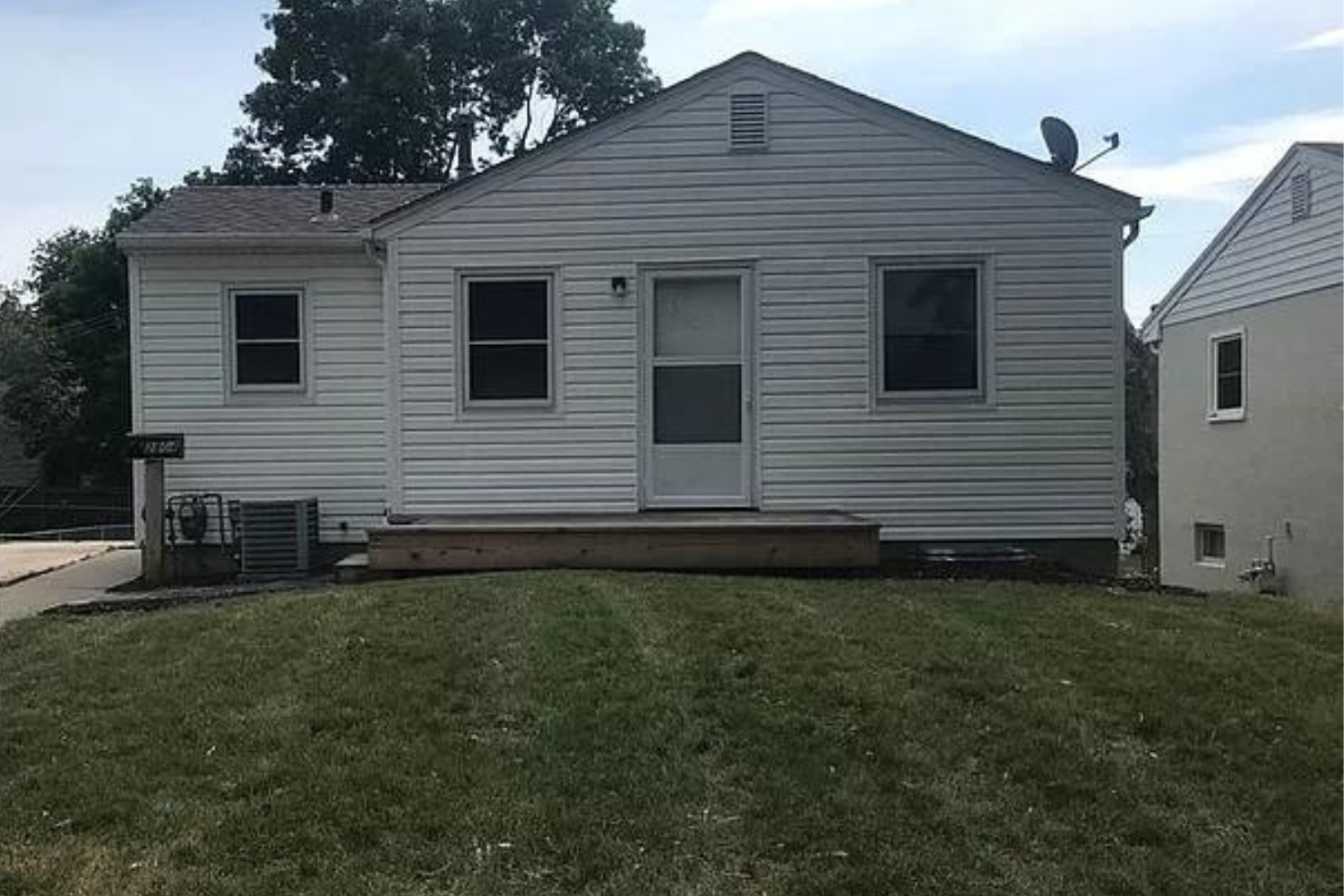 A newly renovated traditional home with white siding and contrasting dark shutters, featuring a gable roof and small wooden entry steps, located at 1907 S Prairie Ave, Sioux Falls, SD.