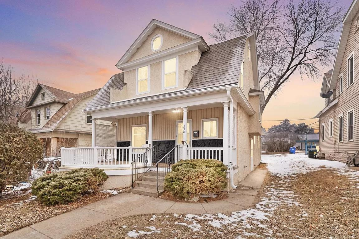 Two-story house with beige siding and covered porch at 830 W 7th St, Sioux Falls, SD during early evening